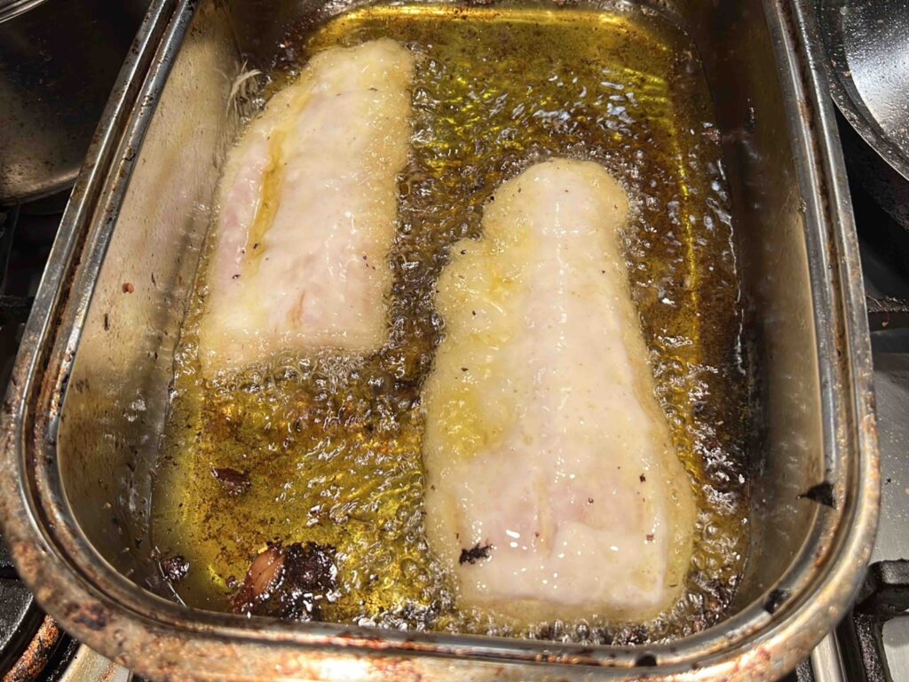 Shallow frying fish fillet in a roasting pan